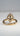 A gold ring with a large oval clear gemstone pavé-set on top of a polished gold band, photographed on a neutral light gray background.